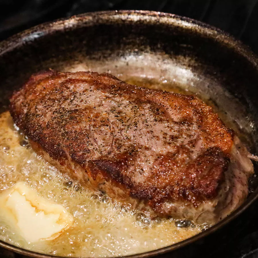 Steak searing in a pan.