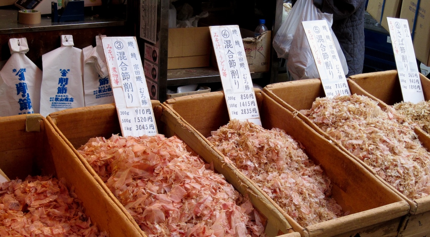 Bins of pink and light brown katsuobushi flakes sit in a marketplace