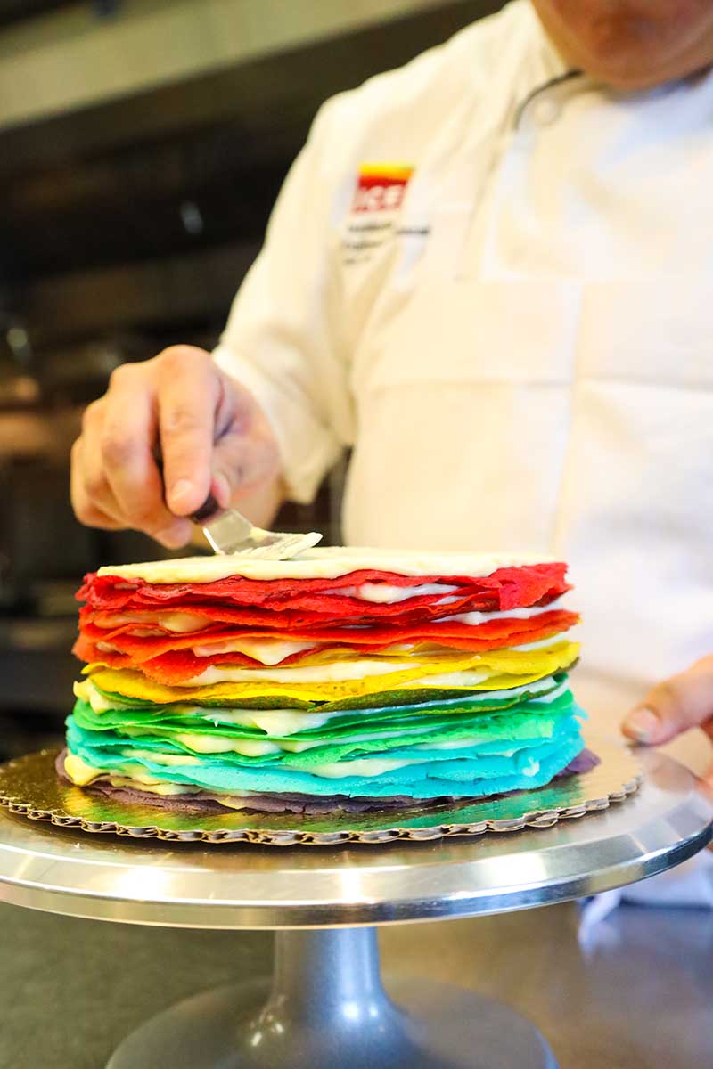 Chef Trung Vu assembling a rainbow crêpe cake.