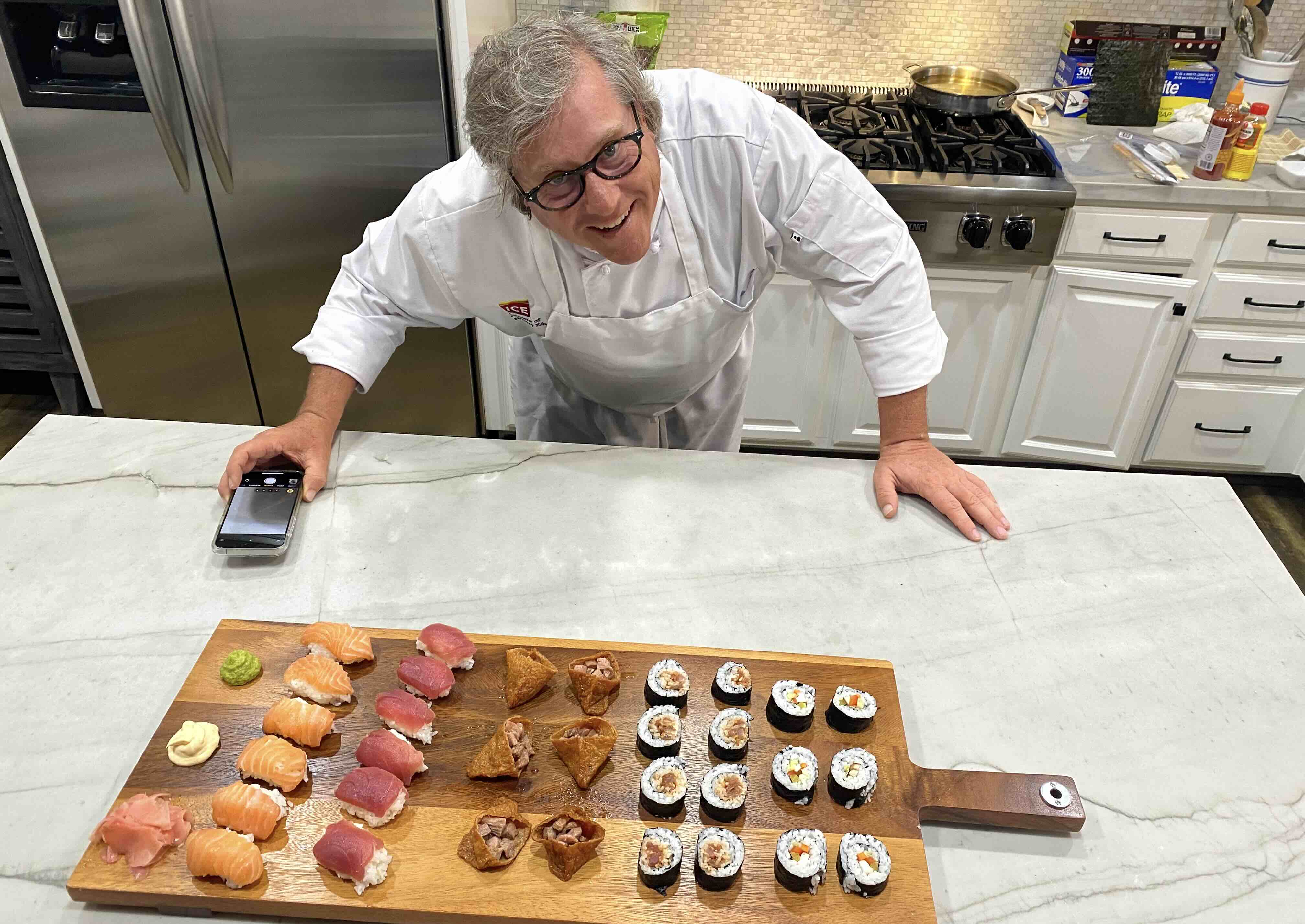ICE online culinary school graduate Jason Sims smiles with a board of prepared sushi
