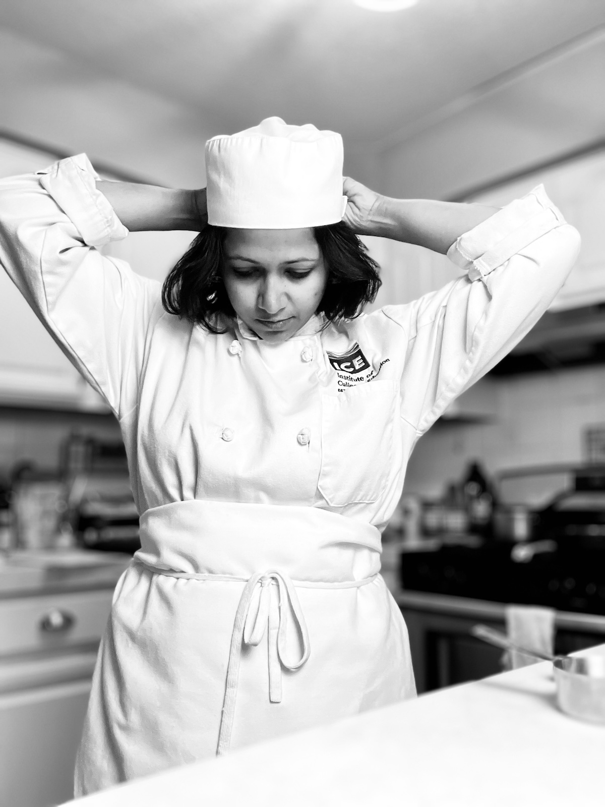 ICE culinary school online graduate Zakia "Trisha" Answary in uniform preparing to cook.