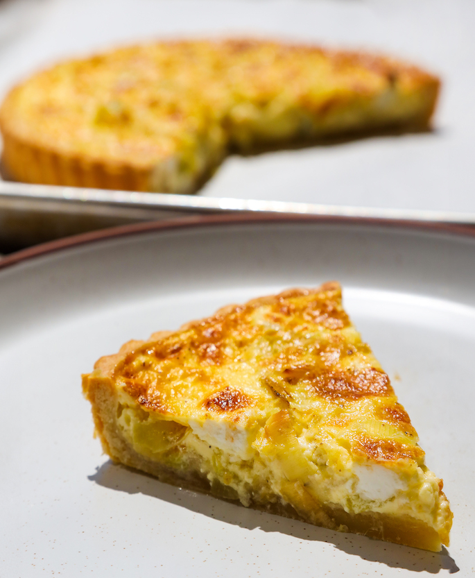Slice of leek and goat cheese quiche plated