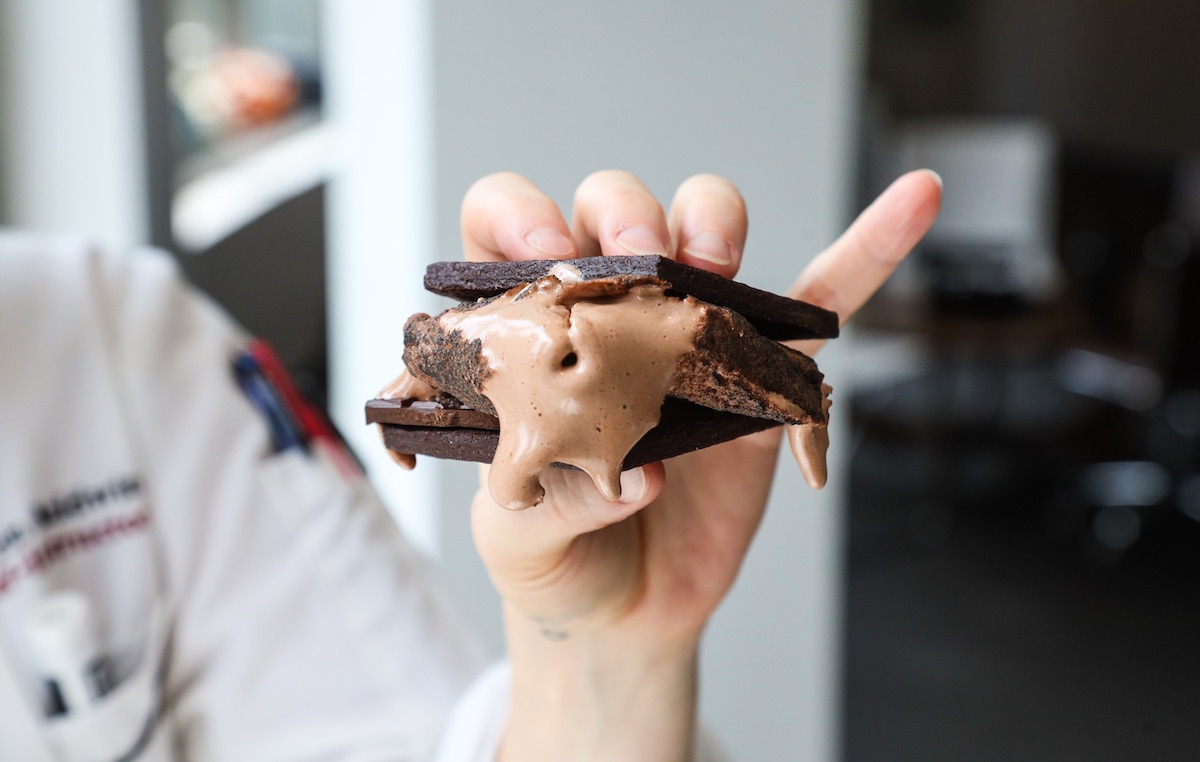 Hand holding a chocolate s'more with toasted oozing marshmallow.