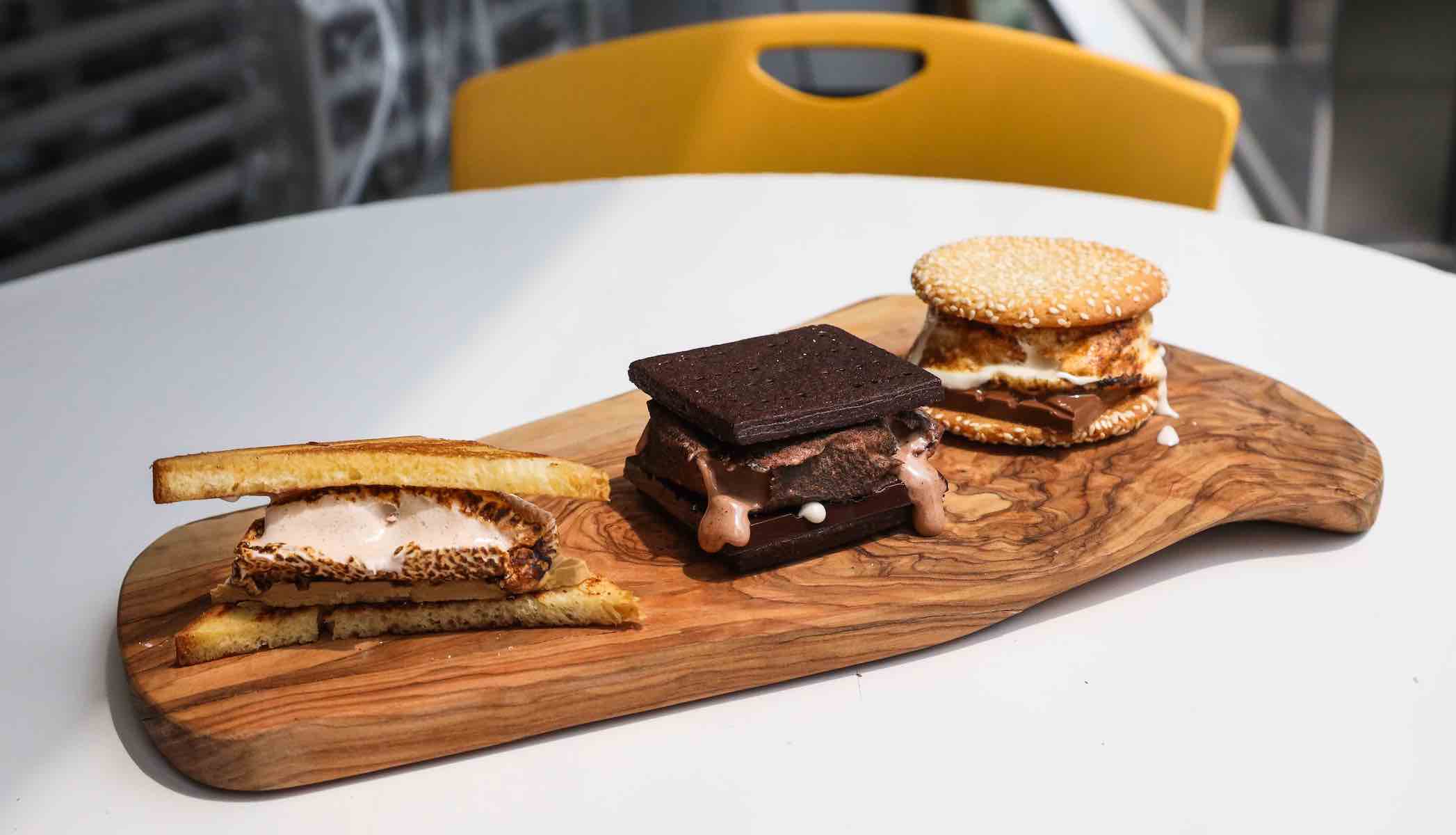 Three toasted s'mores on a wooden board.