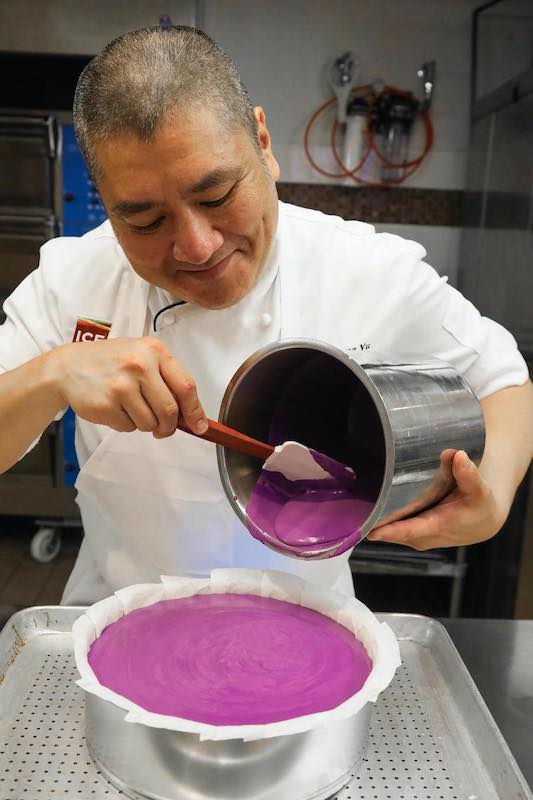 Chef pouring purple cheesecake batter into pan