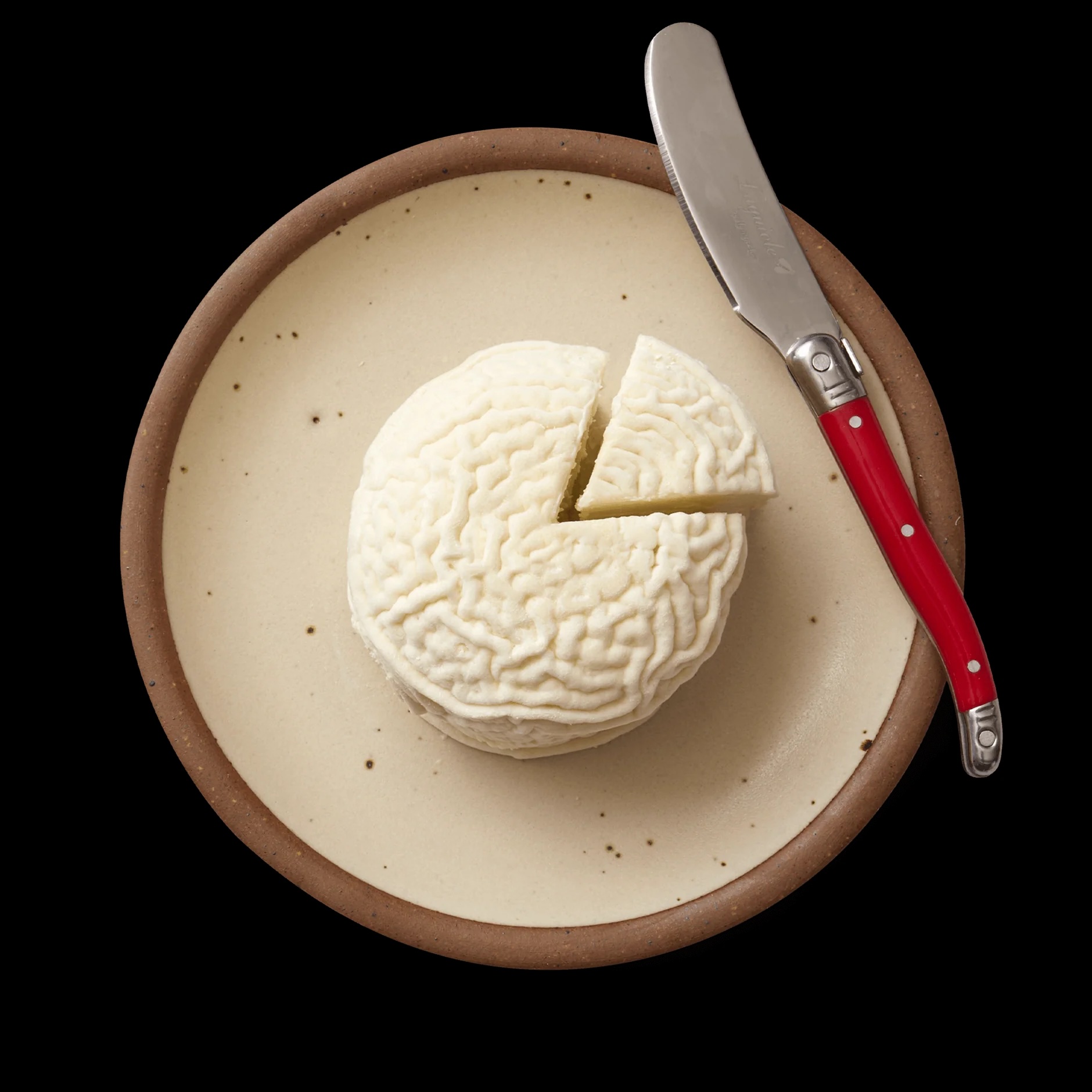 Vermont Creamery's coupole cheese, a white wheel of cheese with brain-like ridges on top, sits on a brown plate