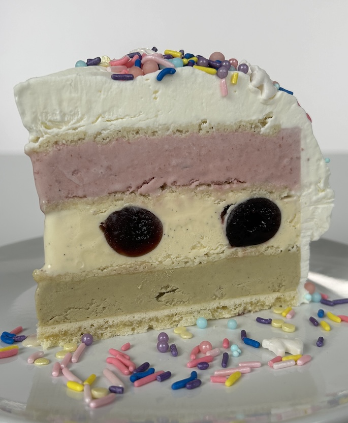 Slice of ice cream cake on a plate with sprinkles