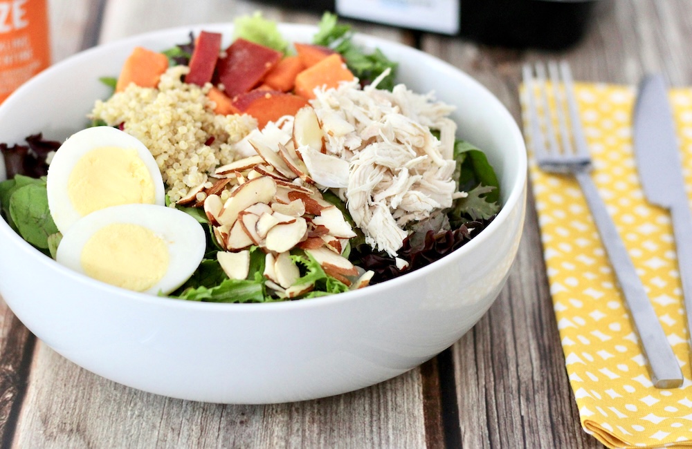 A white bowl filled with salad sits on a wooden table