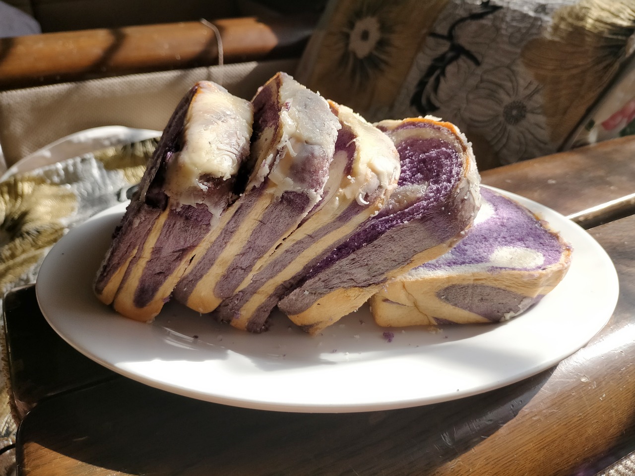 Five thick slices of purple swirled ube bread sit on a white plate.