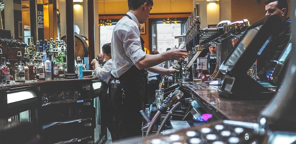 Artistic image of servers behind a bar.