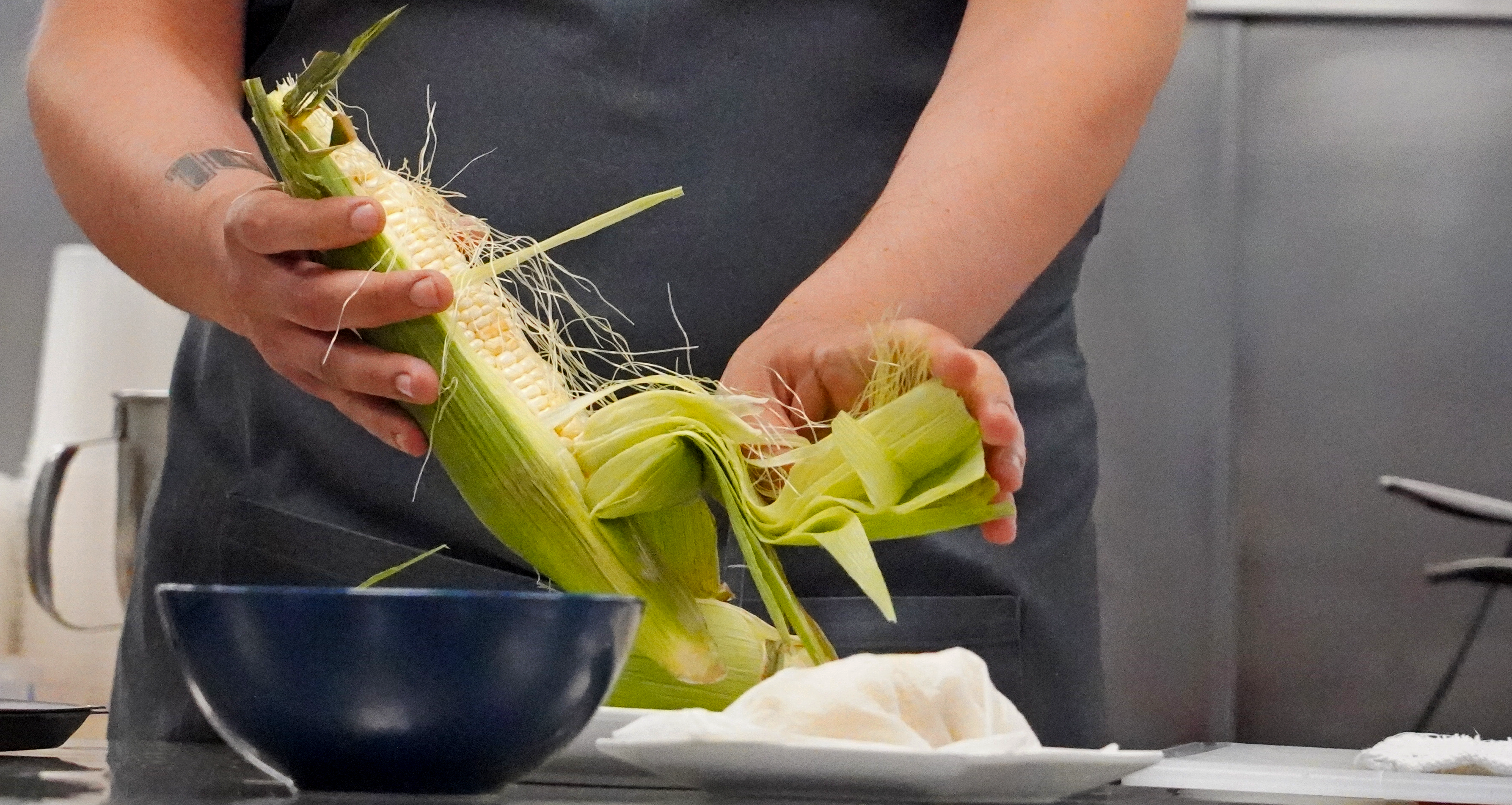 Chef Cervantes shucks an ear of corn
