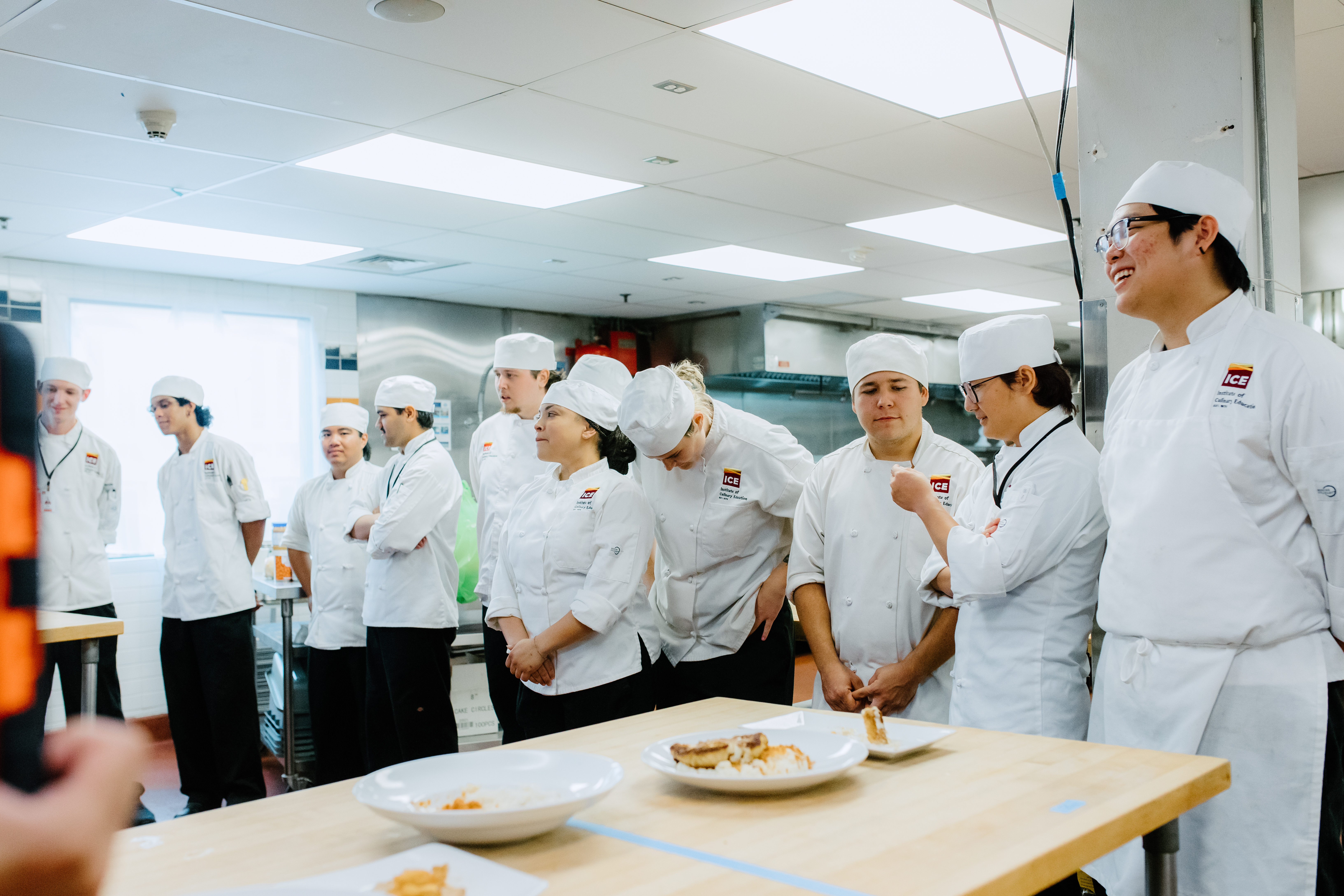 A line of ICE students stands in a kitchen
