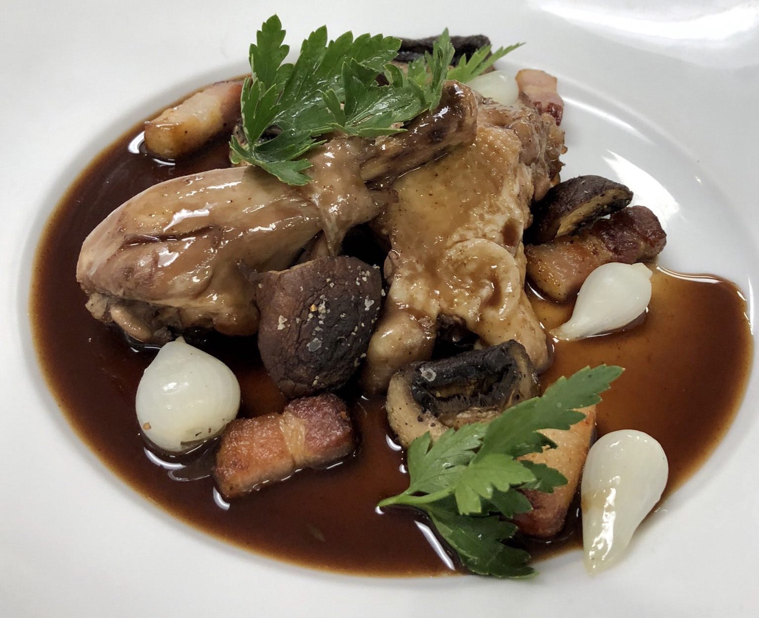 Coq au vin is plated in an ICE Culinary Arts class.