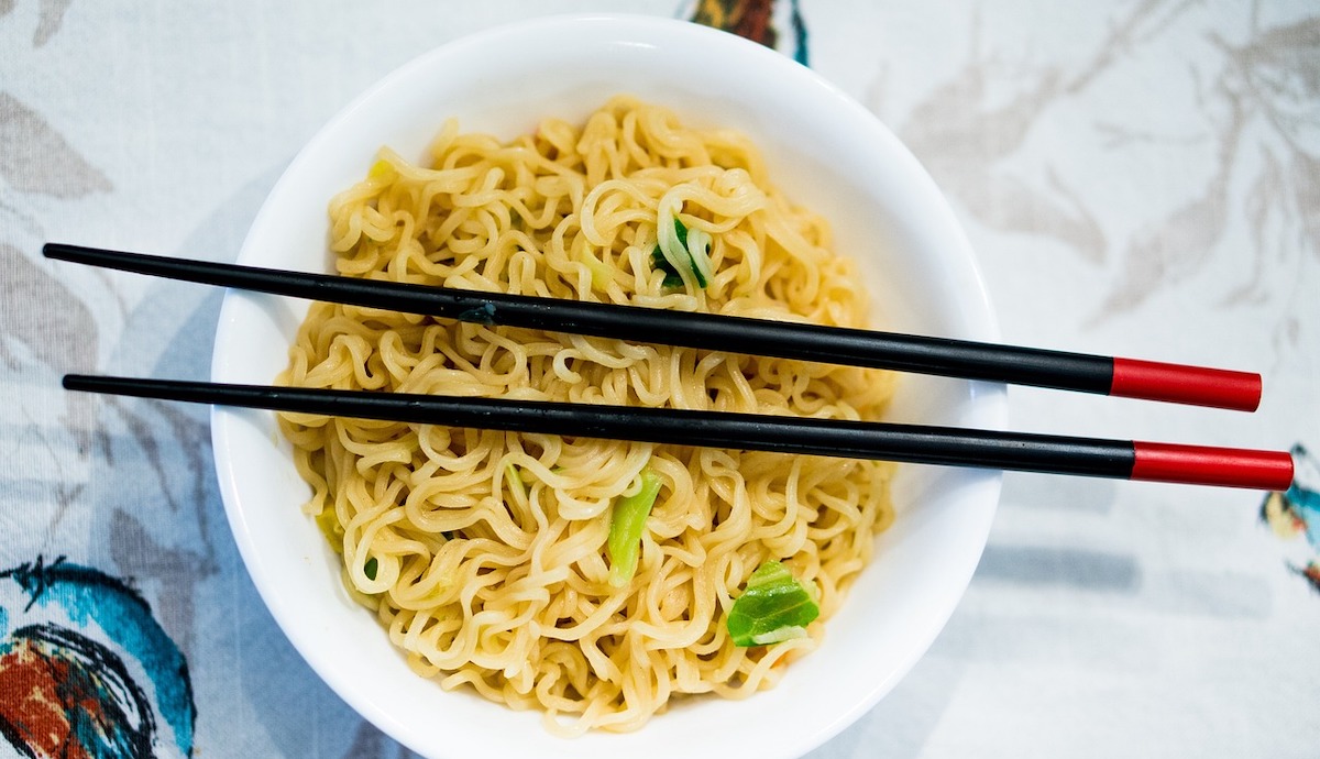 Ramen noodles sit in a white bowl with chopsticks on top