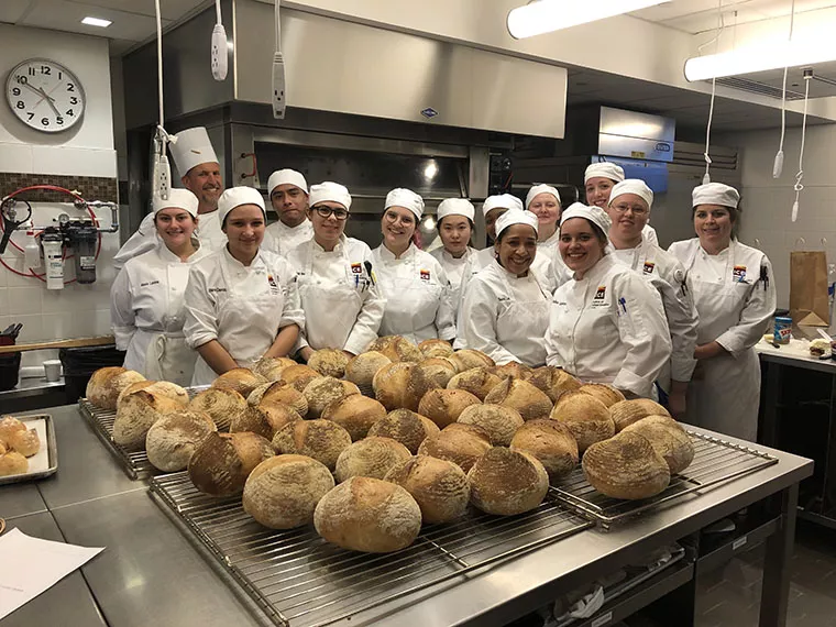 Bread Baking class standing behind a spread of bread.