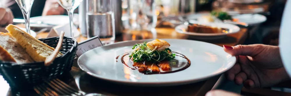 A seafood dish is in focus on a full table.