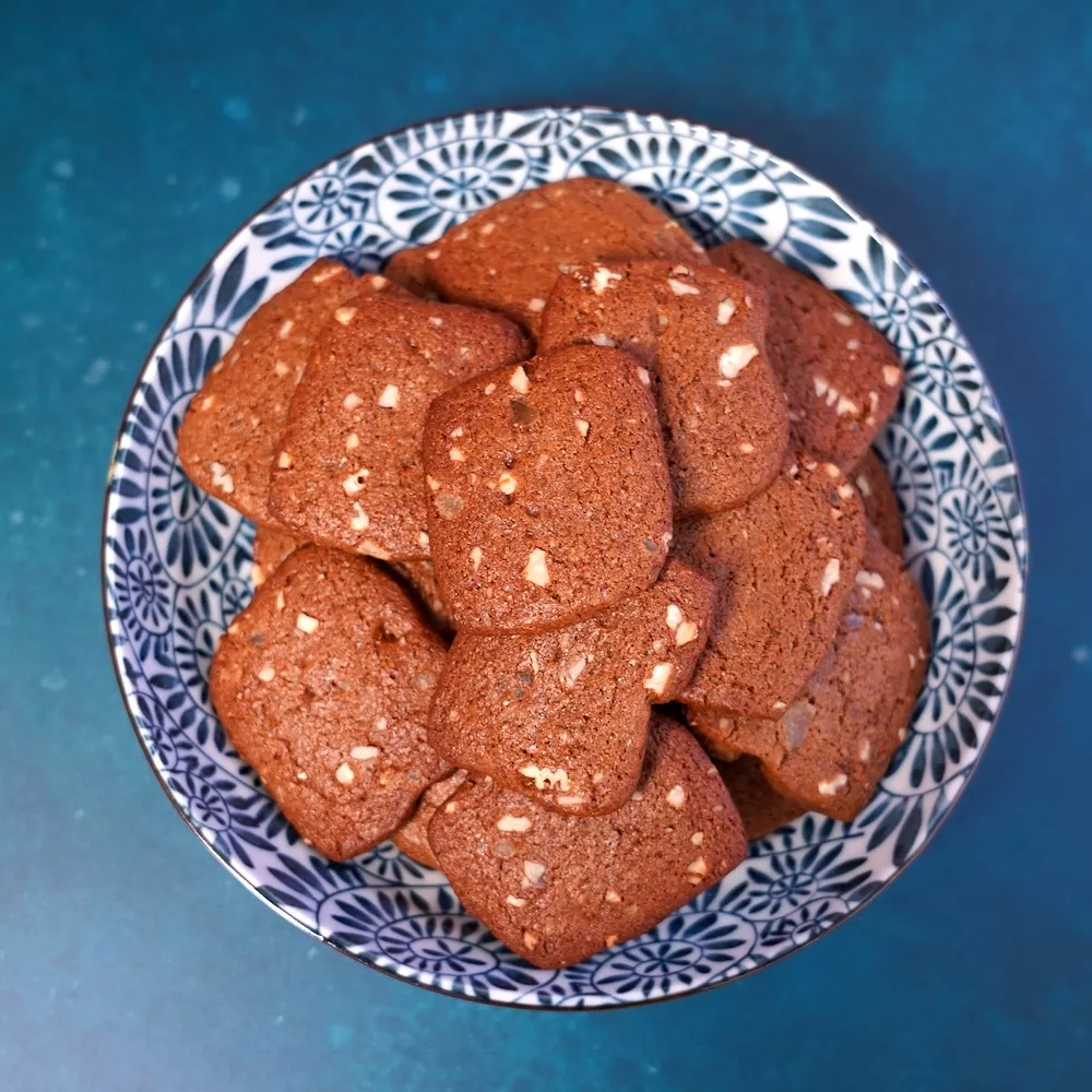 Brown square ginger snap cookies in a blue and white patterned bowl on a brown background