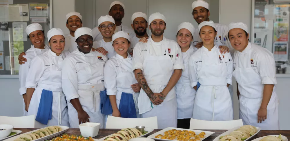 A happy Culinary Arts class poses by their spread of Mexican food