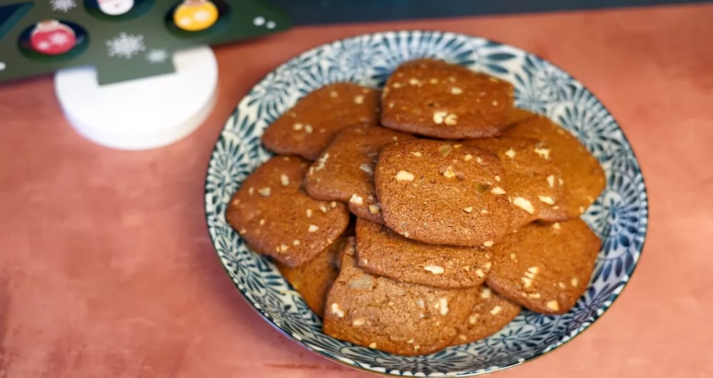 Brown square ginger snap cookies in a blue and white patterned bowl on a brown background