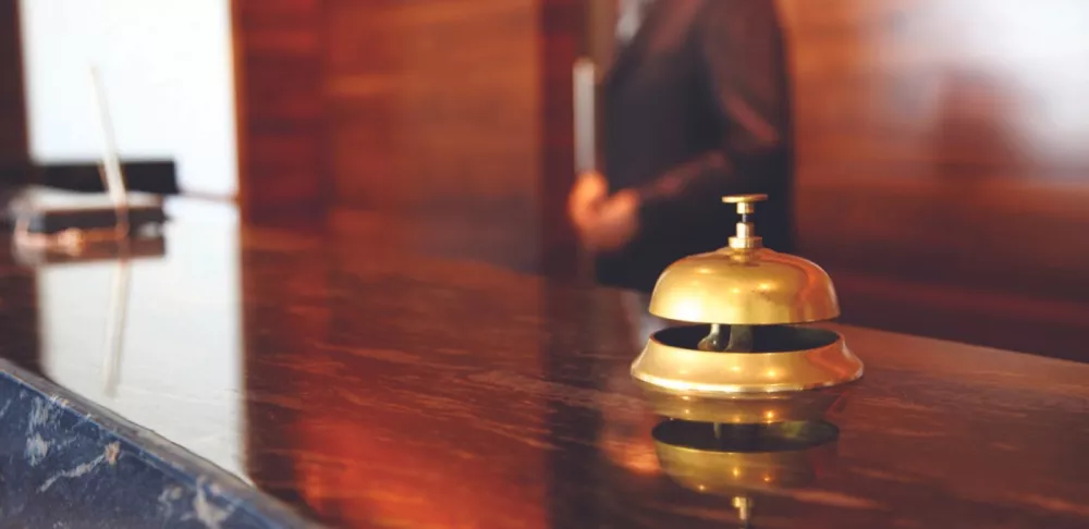 A gold hotel call bell sits on a wooden counter