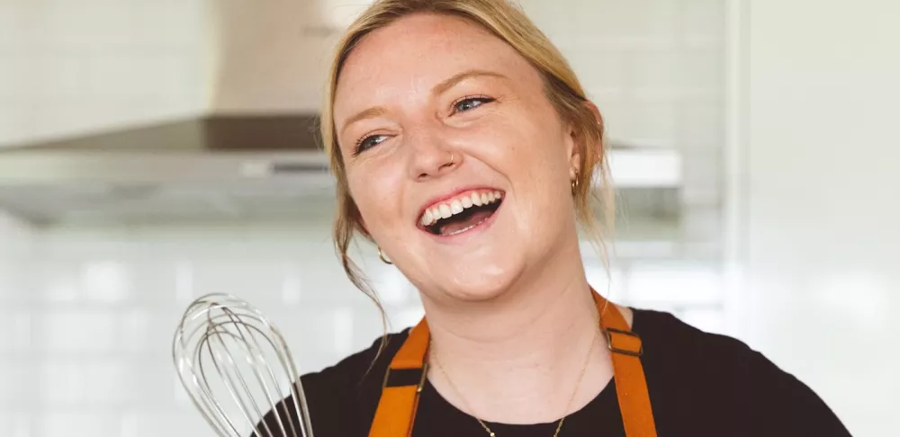 ICE alumna Katie Elliot holds a whisk and smiles