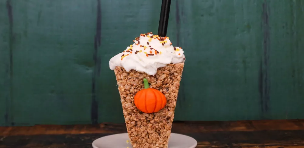 Crispy rice treats shaped into a coffee cup topped with whipped cream and straw