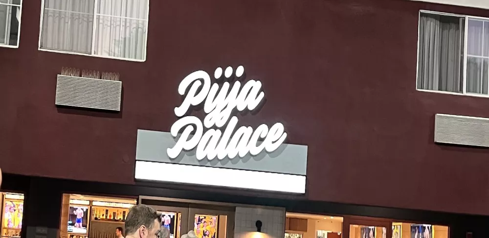 A white sign that reads "Pijja Palace" on the side of a red building