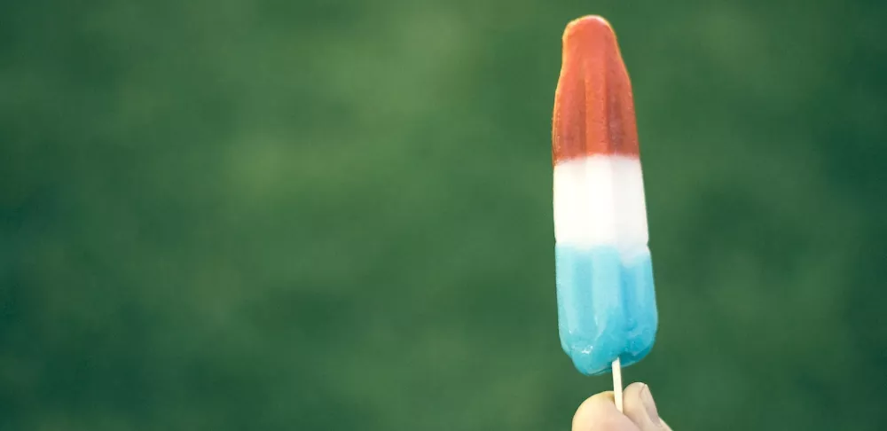 A hand holds a multicolored popsicle