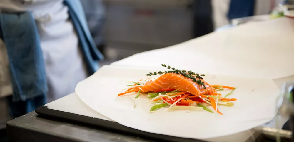 Salmon prepared for poaching with julienned vegetables and aromatics.