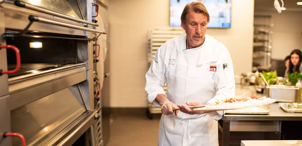 Chef Sim Cass prepares to put pizza in the oven at ICE.