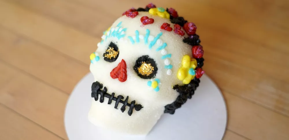 A sugar skull decorated with blue, yellow, red and black icing