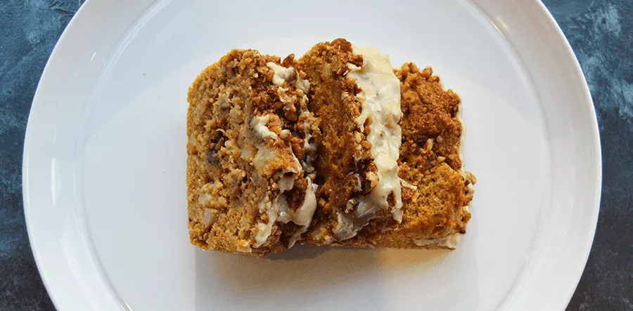 A slice of banana bread sits on a white plate on a blue table