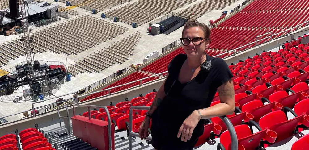 Chef Sandra Gajovsky smiles in front of rows of red chairs lining a stadium