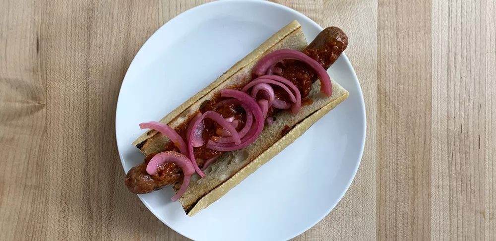 Chef Frank's lamb hot dog with pickled red onions and harissa