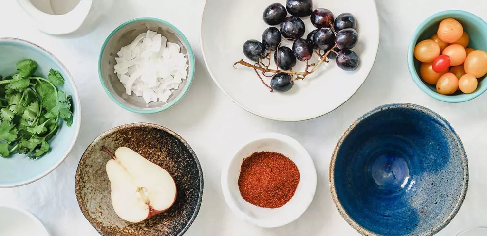 Colorful bowls hold fresh food ingredients and spices