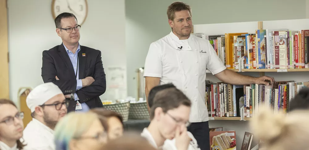 Chef Lachlan listens while Chef Curtis Stone is introduced for a guest lecture.