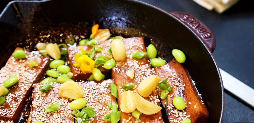 Chef Olivia's plant-based marinated tofu dish sits in a red Staub brand pan