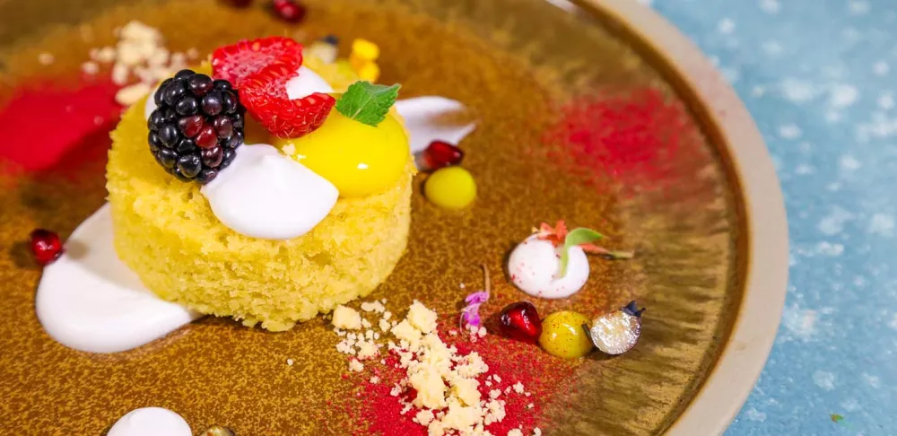 A plated dessert of olive oil cake and seasonal berries.