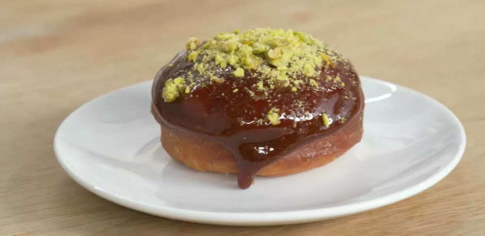 A Sicilian pistachio and calamansi donut sits on a white plate