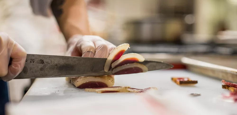 A chef slices duck prosciutto at ICE.