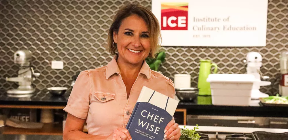 Shari Bayer smiles while holding a copy of her book "Cherfwise"