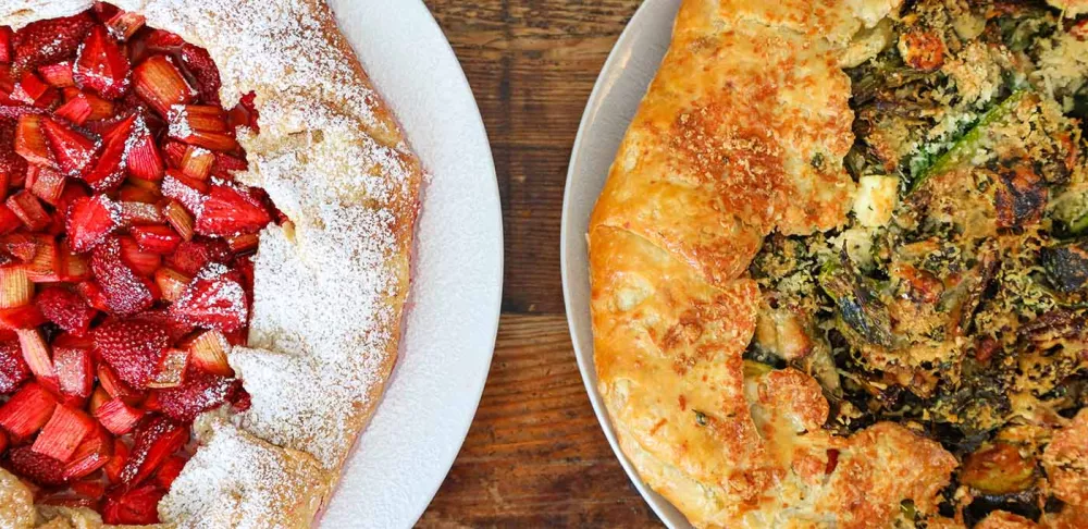 Two spring ingredient galettes on white plates sit on a brown wooden table