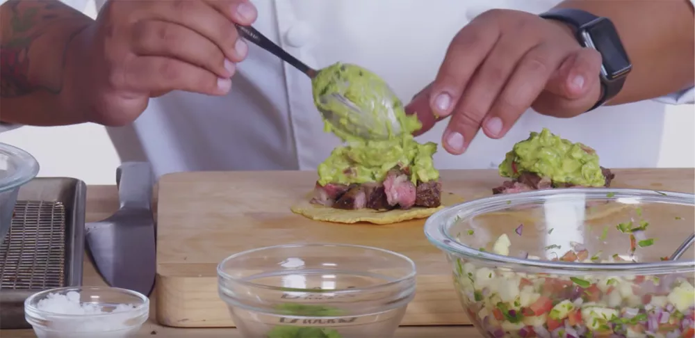 Chef Kelvin's hands top rib-eye tacos with guacamole