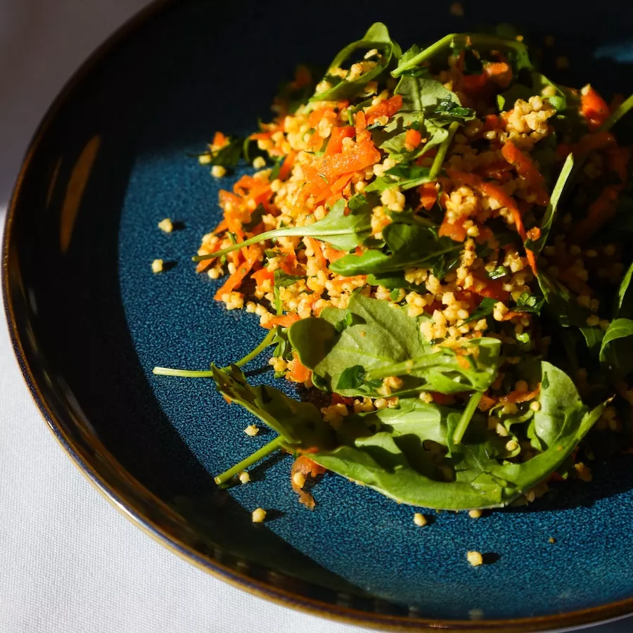 Millet, carrot and herb salad on blue plate