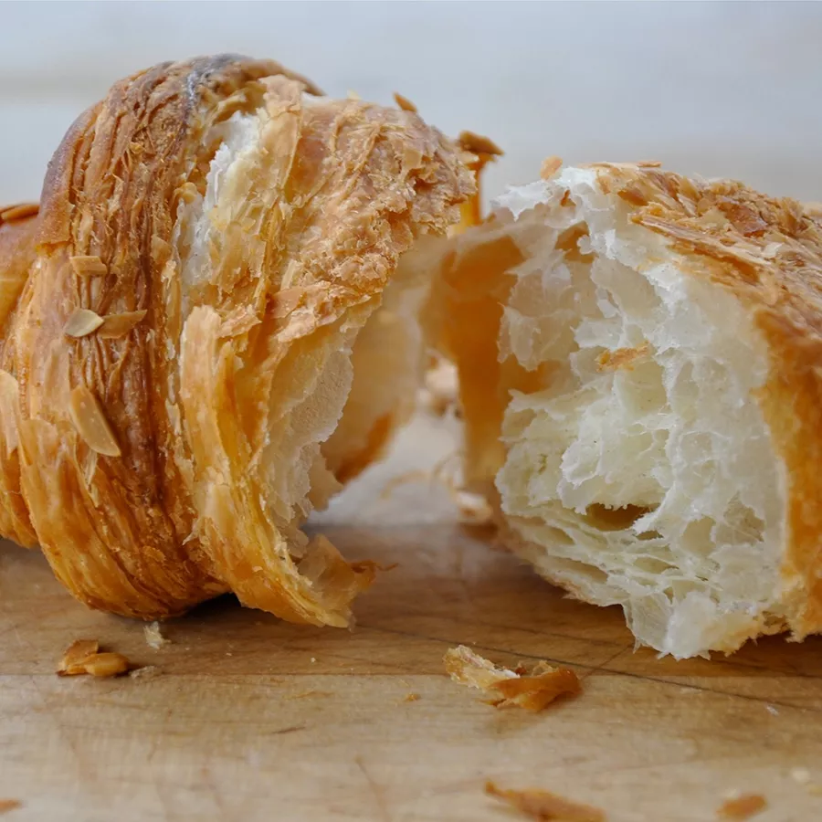 A croissant is cut in half on top of a wooden board