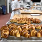 Golden brown croissants on a metal rack on top of a sheet tray