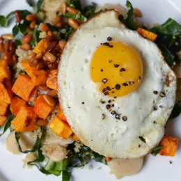 A fried egg over a healthy breakfast spread.