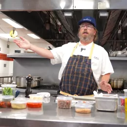 Chef Neal Fraser talks to ICE students behind a table with ingredients on top of it