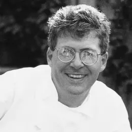 ICE graduate Steven Durfee, a man wearing circular glasses in a white chef's coat, smiles