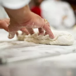 A pastry chef kneads dough to make bread.